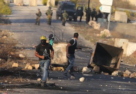 A Palestinian protester runs during clashes with the Israeli troops near the Jewish settlement of Beit El, near the West Bank city of Ramallah, October 15, 2015. REUTERS/Mohamad Torokman