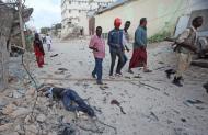 Somalíes pasan junto a un civil muerto cerca de un hotel, que murió cuando estalló un coche bomba ante la puerta de uno de los hoteles más populares de la capital, Mogafiscio, el 27 de marzo de 2015. (AP Foto/Farah Abdi Warsameh)