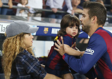 Shakira passes their son Milan to Barcelona's Gerard Pique before the match between Barcelona and Eibar in Barcelona October 18, 2014. REUTERS/Albert Gea