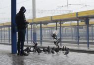 Un hombre alimenta pichones en una estación ferroviaria vacía en Simferopol, Crimea, el sábado 27 de diciembre de 2014. Ucrania bloqueó el viernes todo transporte por tren y autobús entre ese país y la península, que fue anexada por Rusia en marzo. (Foto AP/Anton Volk)