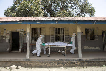 Health workers push a gurney with a dead body at a Red Cross facility in the town of Koidu, Kono district in Eastern Sierra Leone December 19, 2014. REUTERS/Baz Ratner