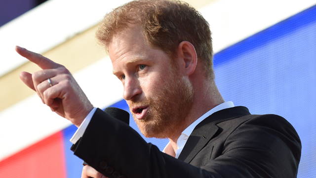 Prince Harry is seen pointing while speaking into a microphone