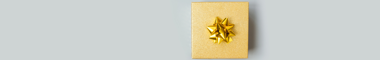 Golden-wrapped gift photographed on a gray background