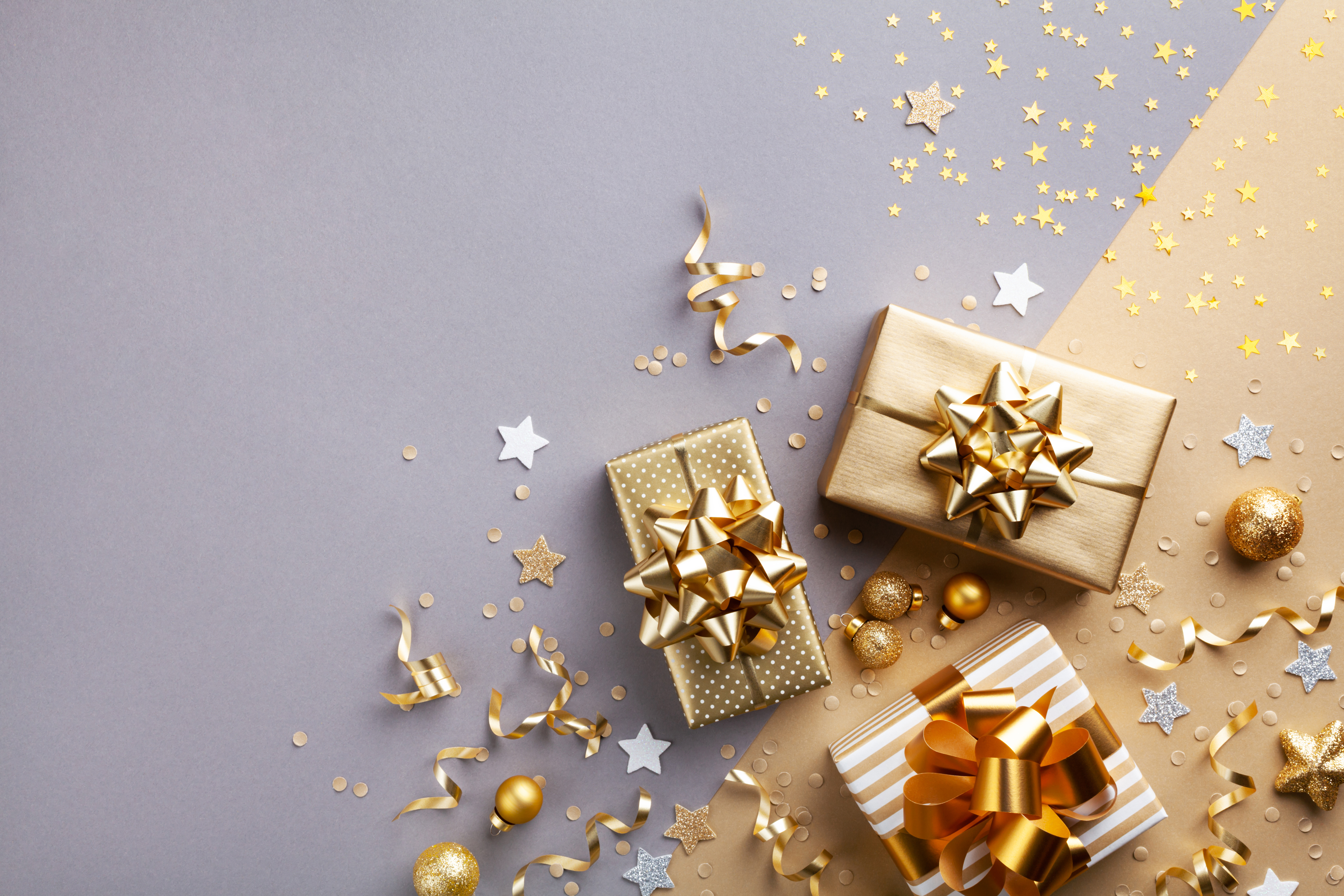 Metallic gift boxes with bows and star confetti shown in a top-down view