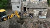 Utility workers operate next to a crater in the courtyard of a hospital in Kharkiv