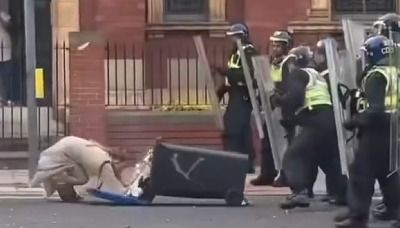 Shocking moment woman shoves wheelie bin towards cops before falling on her face