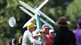 Bryson DeChambeau carries sign out of his way during second round play of the Masters