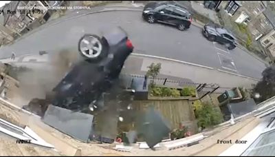 Video shows moment speeding BMW skids across road, flips and crashes into homes