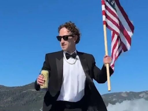 Mark Zuckerberg surfs while drinking beer, holding flag. Rival Elon Musk can’t resist snark