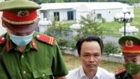 Trinh Van Quyet is escorted by policemen into court at the start of his fraud trial in Hanoi