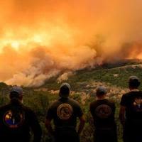 Firefighters watch as flames and smoke move through a valley in the Forest Ranch area of Butte County as the Park Fire continues to burn near Chico, California, on July 26, 2024