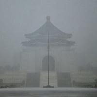 A visitor takes photographs in front of the Chiang Kai-shek Memorial Hall in heavy rain caused by Typhoon Gaemi in Taipei