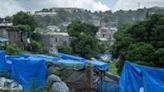 A woman walks past tents in a makeshift camp where migrants live at the Cavani stadium in Mamoudzou on the French island of Mayotte