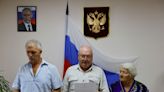 Beneath a portrait of Putin, some Ukrainians embrace Russian passports