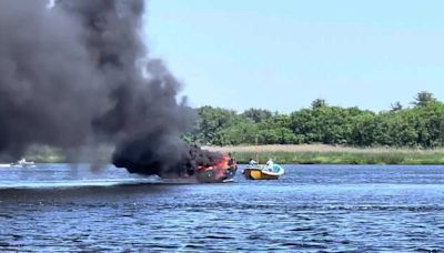 Black smoke billows from burning boat stuck in mud on Mass. river