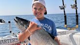 Young man embraces the utter fun of fishing; catching a really big fish helps