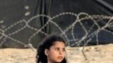 A girl stands behind barbed wire at a camp for displaced Palestinians in Rafah in the southern Gaza Strip on April 30, 2024