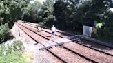 Trespassers pose on chair for photoshoot in middle of railway tracks