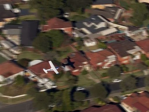 Small plane loses power and skims suburban rooftops before making safe crash landing on belly