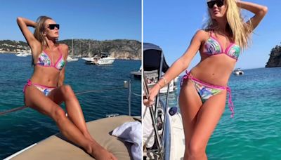 Amanda Holden hangs off the side of a boat in tiny bikini