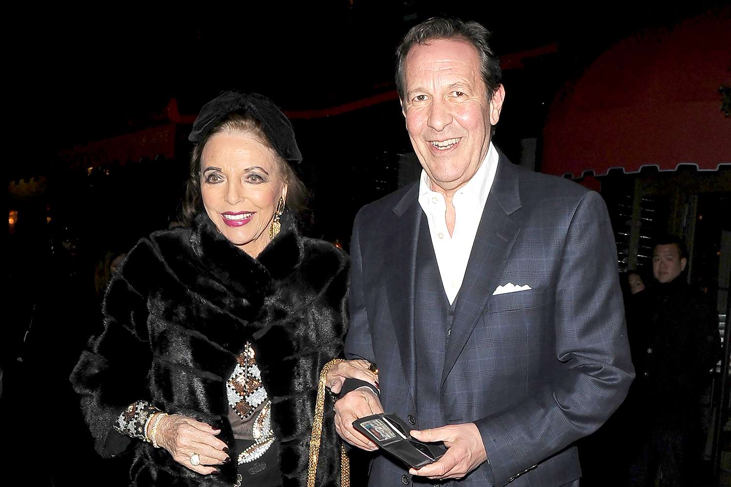 Joan Collins, 90, Wears Sheer, Embellished Top and Oversize Bow for London Date Night with Her Husband Percy Gibson