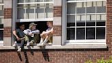 Garfield High School students, on lockdown after a shooting outside of their school, sit at a window as they wait to be released from school on Thursday, June 6, 2024, in Seattle.