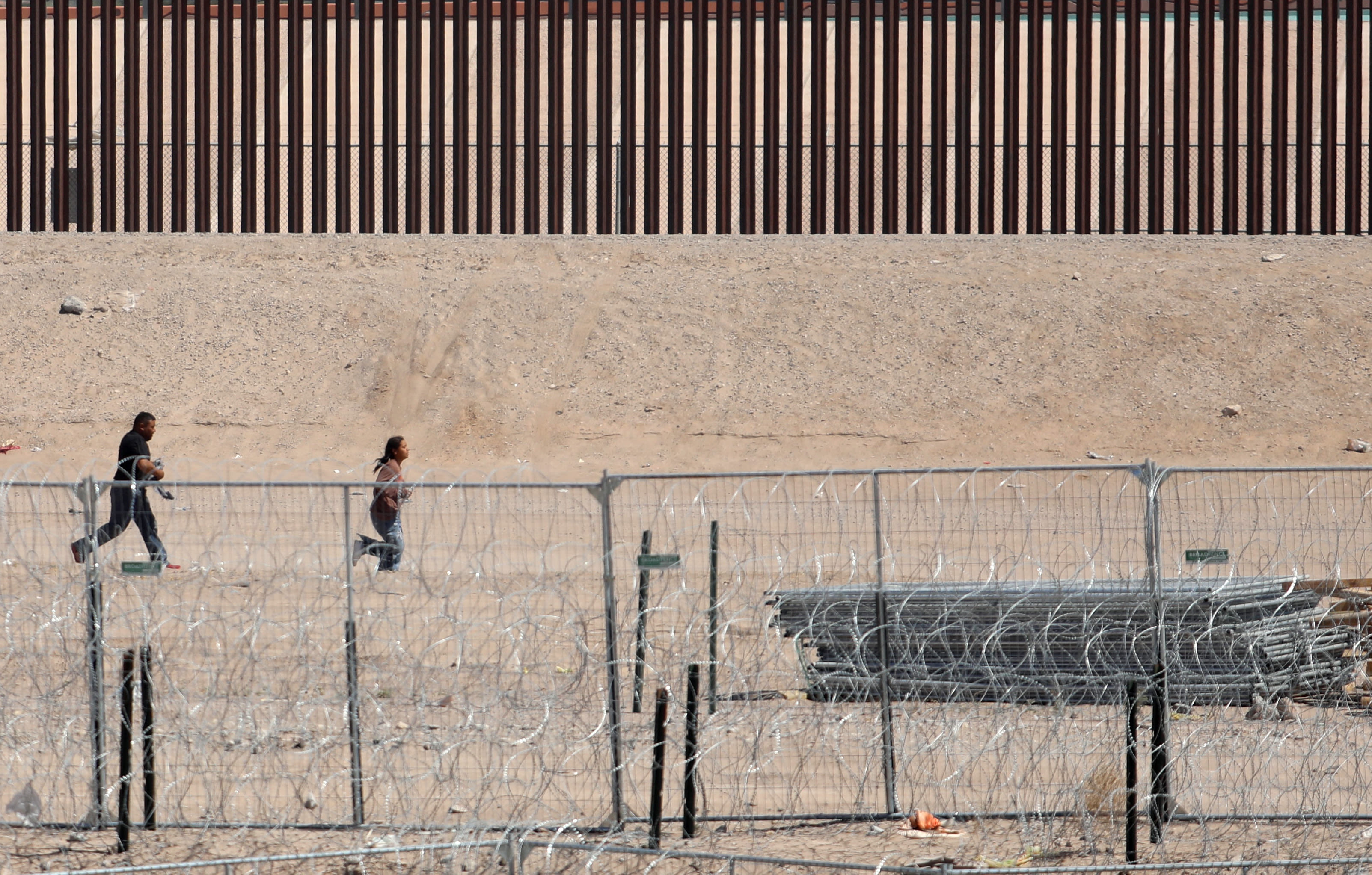 Video shows migrants rush border wall, try to climb over