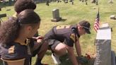 High school football players plant flowers, pay tribute to veterans buried in an Oakmont cemetery