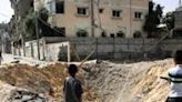 Children stand near a crater caused by Israeli bombardment in a street in Rafah in the southern Gaza Strip on May 18, 2024