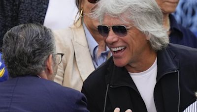 Jon Bon Jovi helps talk a woman off the ledge of a bridge while filming a music video