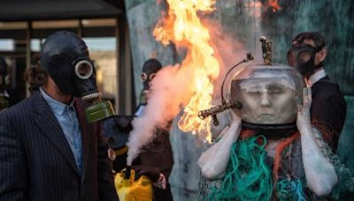 'Ocean goddess' pretends to drown in fake oil as flames engulf climate protest in London