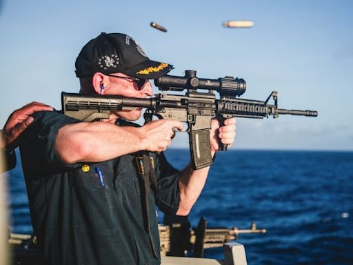 A US Navy warship commander was relieved of duty over a 'loss of confidence' 4 months after he was photographed firing a rifle with a backward scope