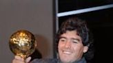 Diego Maradona poses with the 'Golden Ball' trophy at the Lido in Paris on November 13, 1986