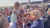 Little girl looks bemused as Trump signs autograph on her hand in permanent marker