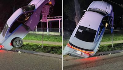 Car crashes and lands vertically on street sign, woman arrested for drunken driving