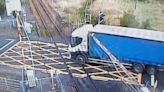 Moment lorry drives through descending railway barrier