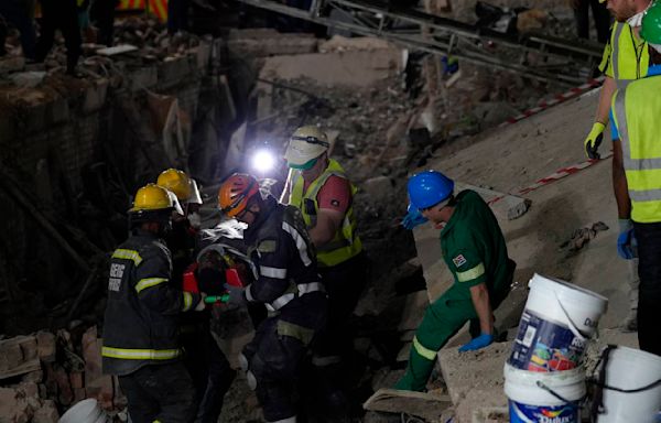 Rescuers bring out survivors from the rubble a day after a deadly building collapse in South Africa