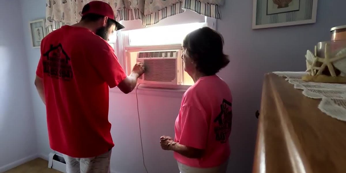 Man helping older residents beat the heat by installing their air conditioners for free