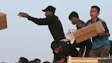 Palestinians take boxes of humanitarian aid after rushing the trucks bringing it from the US-built Trident Pier near Nuseirat in the central Gaza Strip on May 18, 2024