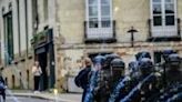 Police in riot gear stand in formation as they are pelted with fireworks during a May Day rally in Nantes, western France