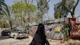 A displaced Palestinian woman holds a child by the hand as she walks in front of tents set up inside the European hospital compound in Khan Yunis in the southern Gaza Strip