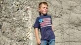 Young Liam Fisher lay down next to the fossilized leg bone of a dinosaur he discovered in the Badlands of North Dakota in 2022, and his family sent the photograph to a paleontologist friend, who confirmed it to be of...