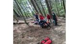 Mountain rescue team help evacuate injured mountain biker from woods
