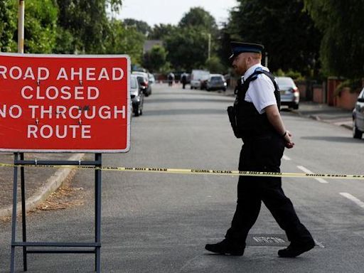 A police officer patrols a closed road near the scene where a teenage suspect was arrested after people were stabbed in Southport