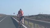 Sin casco y sin ropa pero con riñonera y en bici por una carretera de Lanzarote