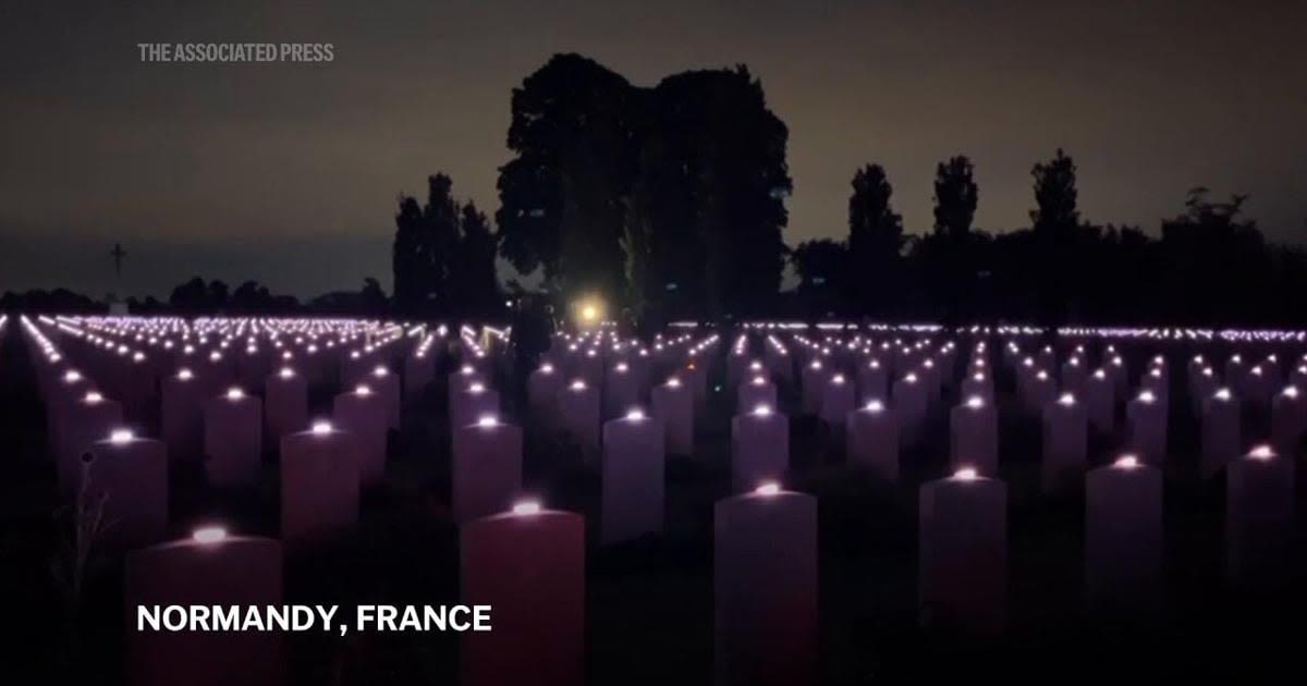 Tombstones of fallen WWII soldiers lit up at cemetery in Normandy as part of D-Day commemorations