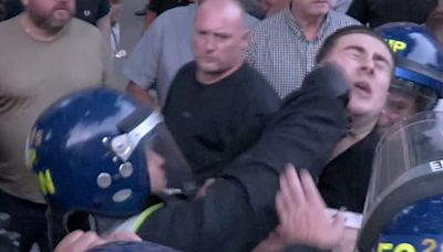 Moment police officer punches protester repeatedly in the face