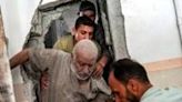 A man is helped to evacuate from a building in Nuseirat, central Gaza, after Israeli bombardment