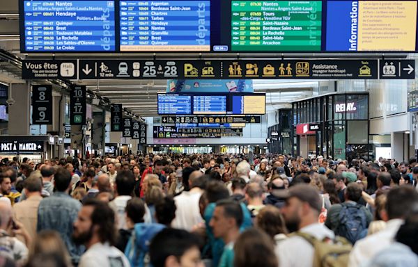 Passengers wait after France’s train network hit by 'massive attack' before the Olympics