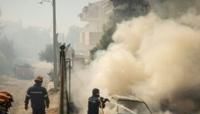 Firefighters battle a burning car during a wildfire in the Athens suburb of Dione